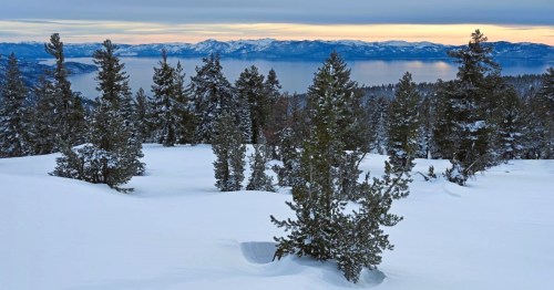 Sunset views of Lake Tahoe, surrounded by snowcapped mountains from the snowy overlook at Chickadee Ridge in Nevada.