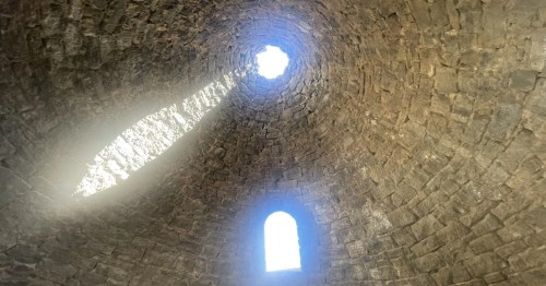 Interior view of a stone charcoal oven at Ward Charcoal Ovens State Historic Park in Ely, Nevada, showing the conical brick walls and sunlight shining through the upper openings.