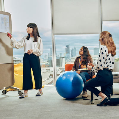 ثلاثة زملاء عمل يتبادلون النقاش أمام لوحة.