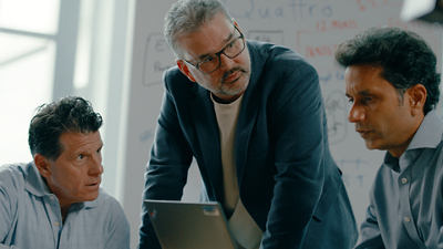 Three people talking in a conference room in front of a white board