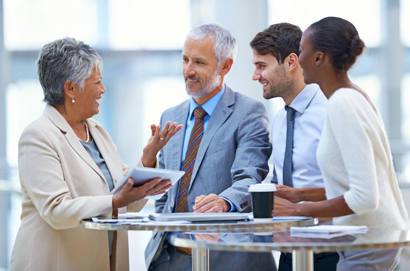 Four people in business attire standing by a high table