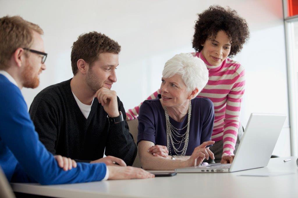 Four people sitting in front of a computer