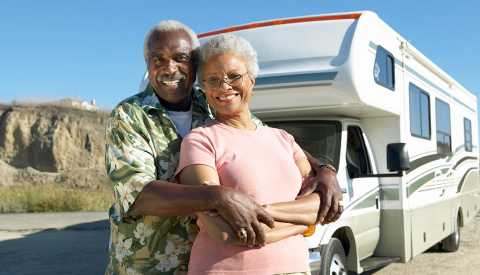 a happy couple standing in front of their r v