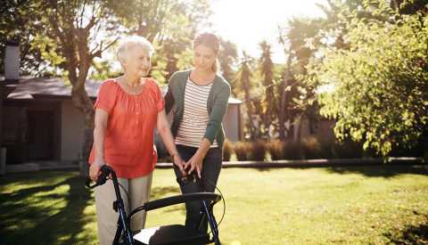 A woman using a walker outside as her adult daughter assists her