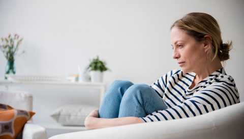 woman sitting in armchair holding legs