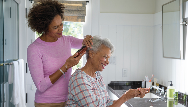 a woman brushes the hair of an older woman