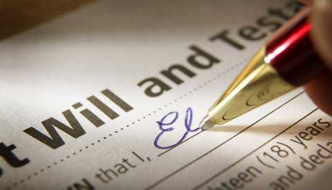 closeup of the signing of a last will and testament with a red and gold ballpoint pen writing in blue ink