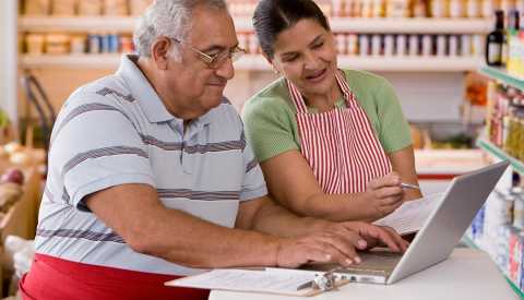 Una pareja mayor hace las cuentas de su negocio frente a una computadora 