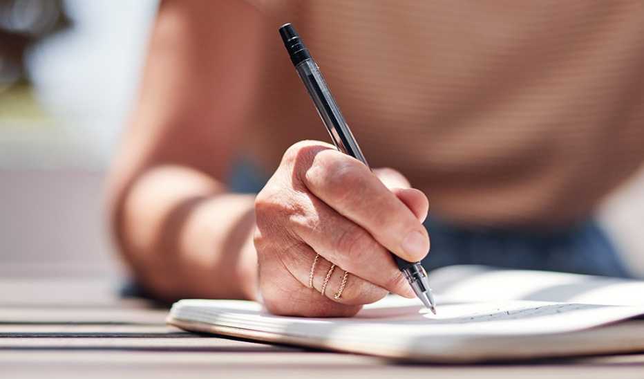 A cropped shot of a woman's hand writing in a journal