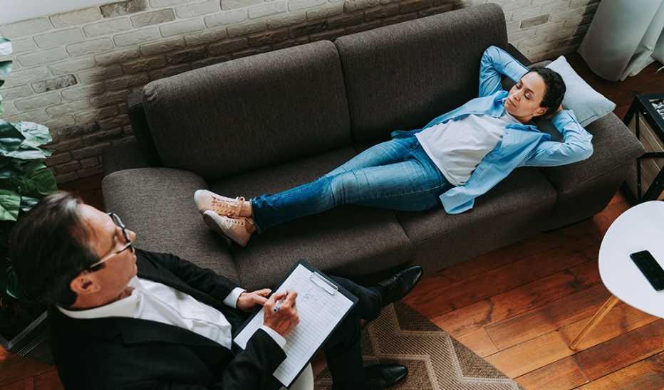 A woman lying on a couch beside a male therapist in a chair