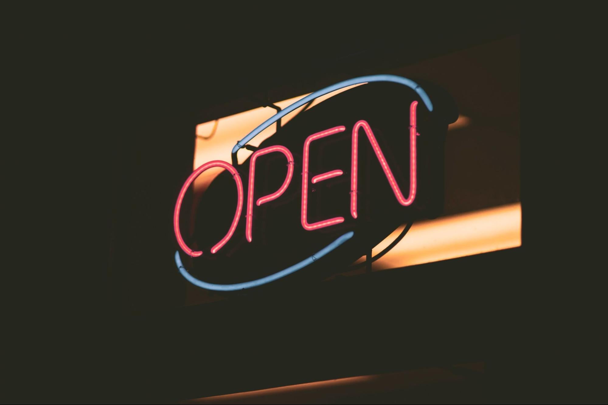 A neon sign in the dark declares a store is open