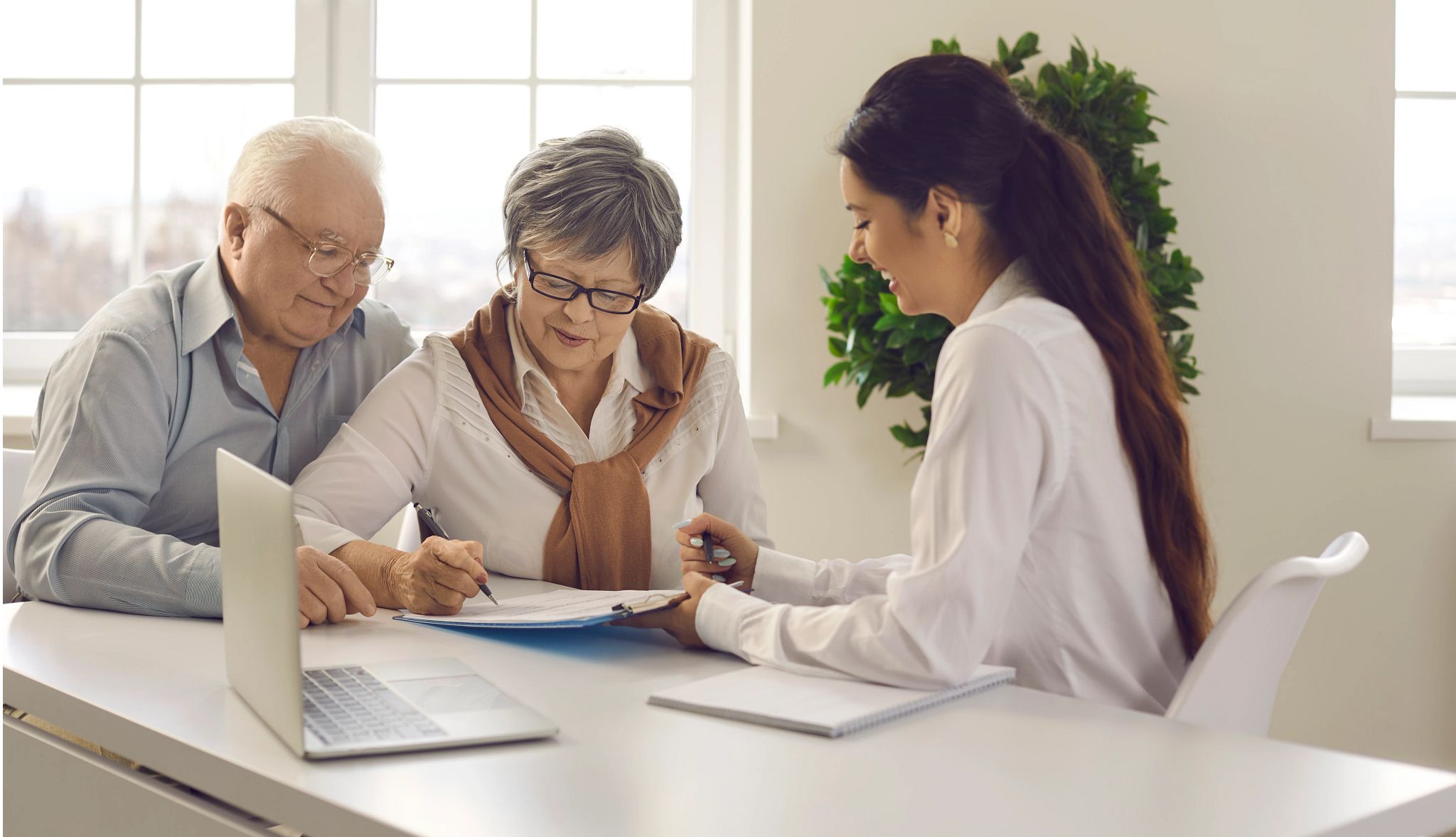 Old married family couple signing contract agreement. Aged lady putting signature on paper document. Young financial adviser consultant friendly smiling to customers client. Savings bank investment