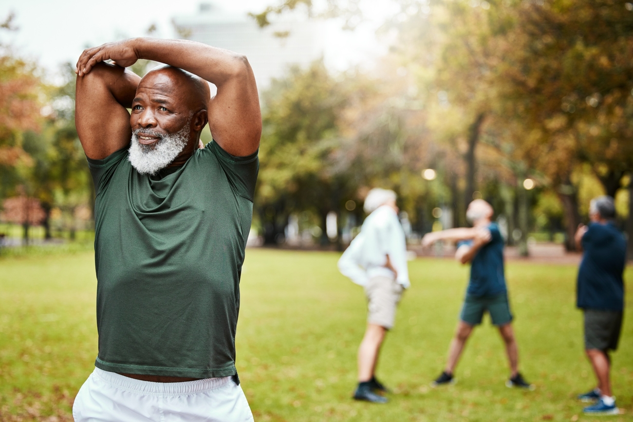 A senior man stretching in a park.