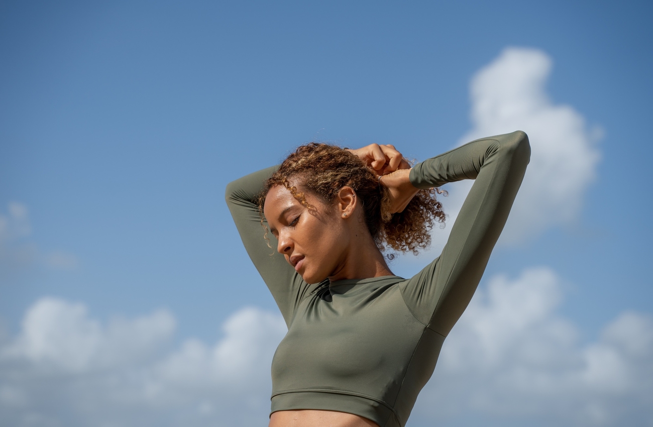 A woman wearing a green sports bra and shorts.