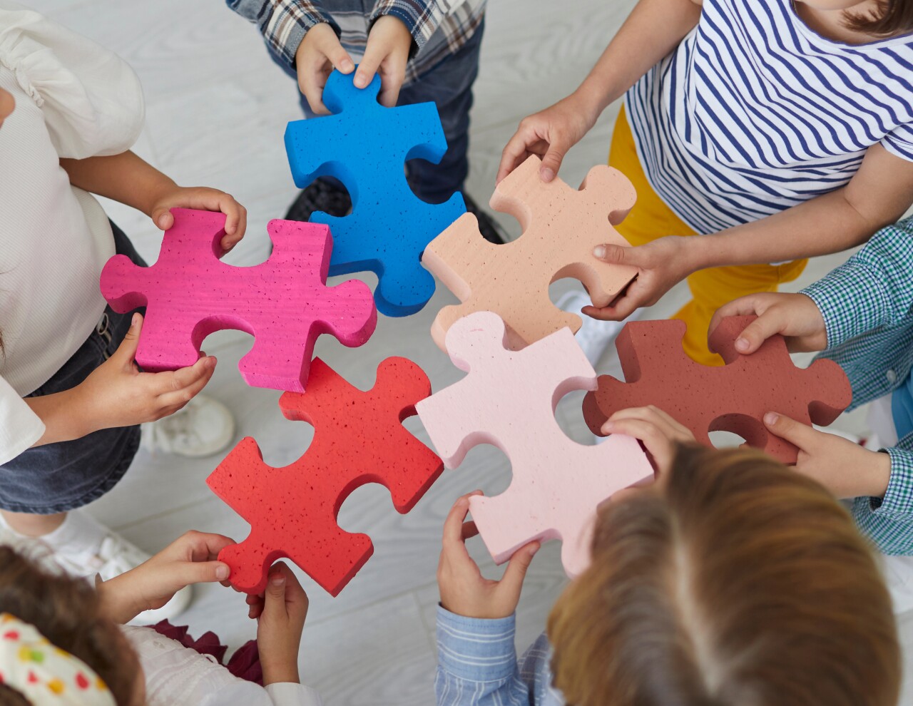 Team of school kids standing in the classroom and joining pieces of a jigsaw puzzle