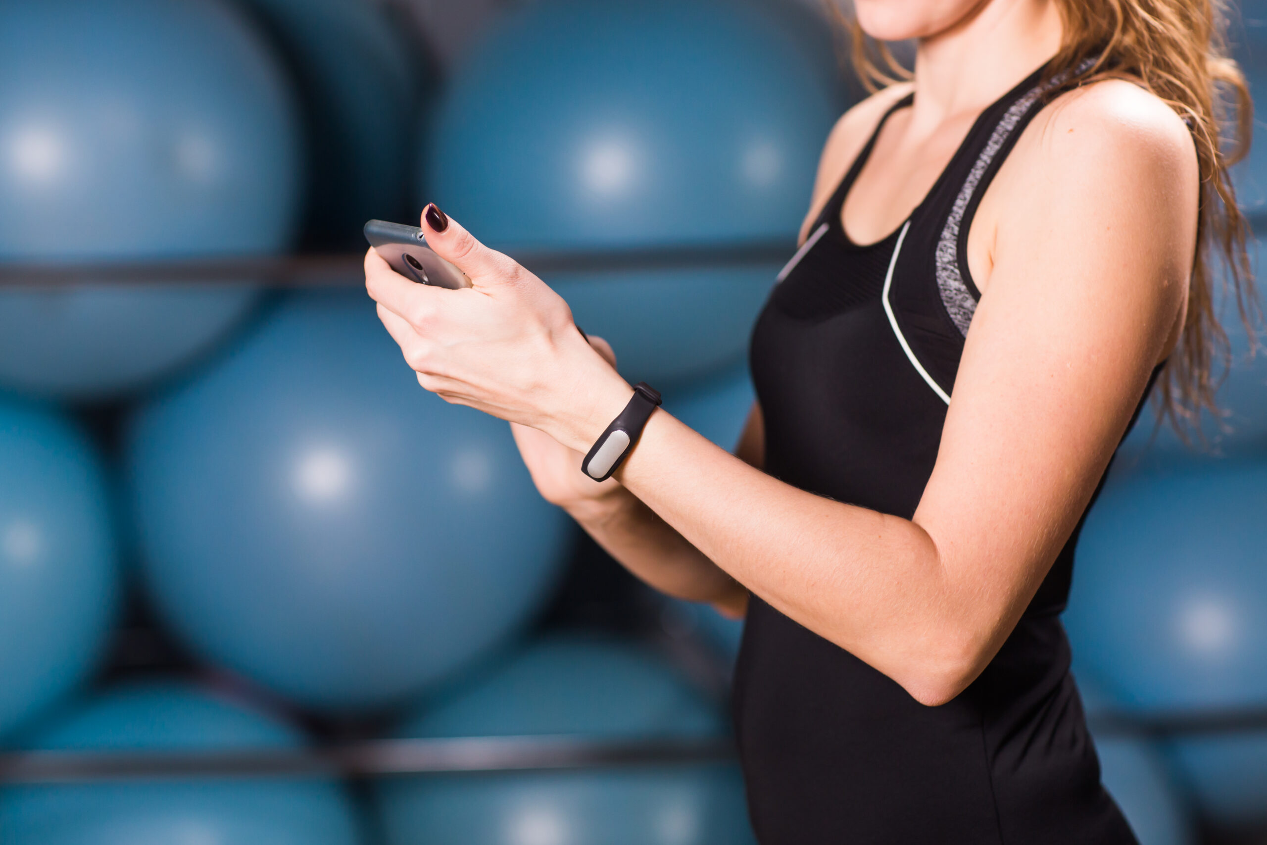 Close up of female hands with fitness tracker and smartphone in gym