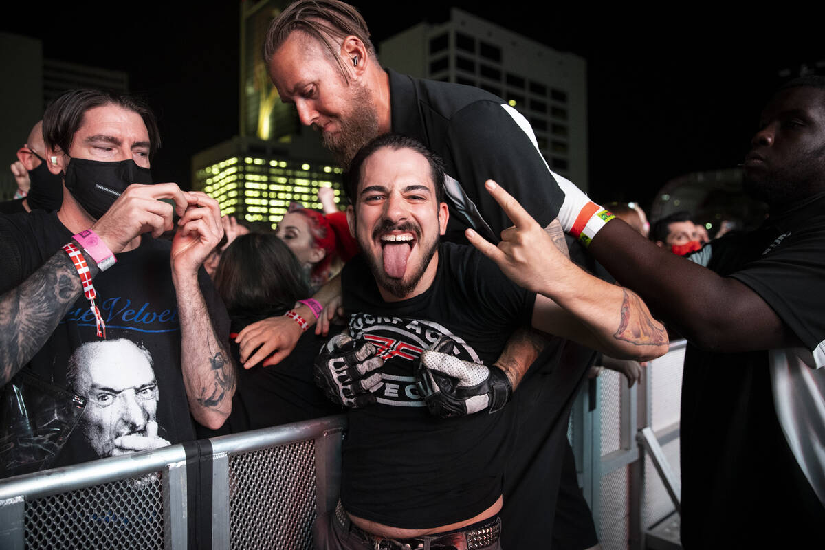 A person poses as he is grabbed by security guards after crowd surfing during a performance by ...