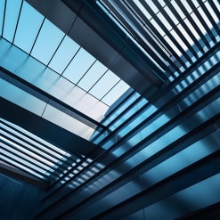 An upward perspective shot of a modern architectural interior, with geometric metal structures across the glass.