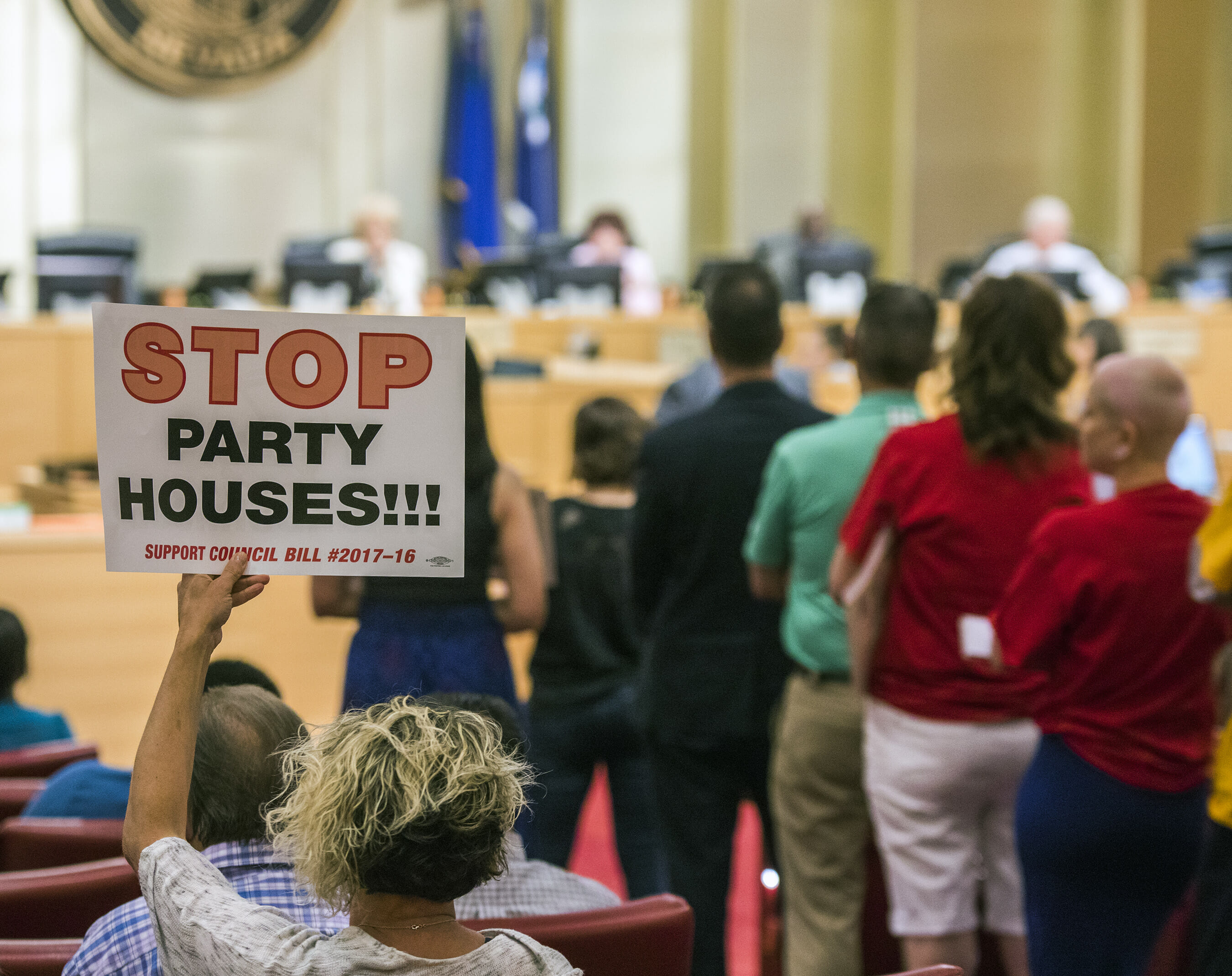 A woman raises a sign while people wait to speak during the Las Vegas City Council meeting regarding short-term home rentals on June 21, 2017.