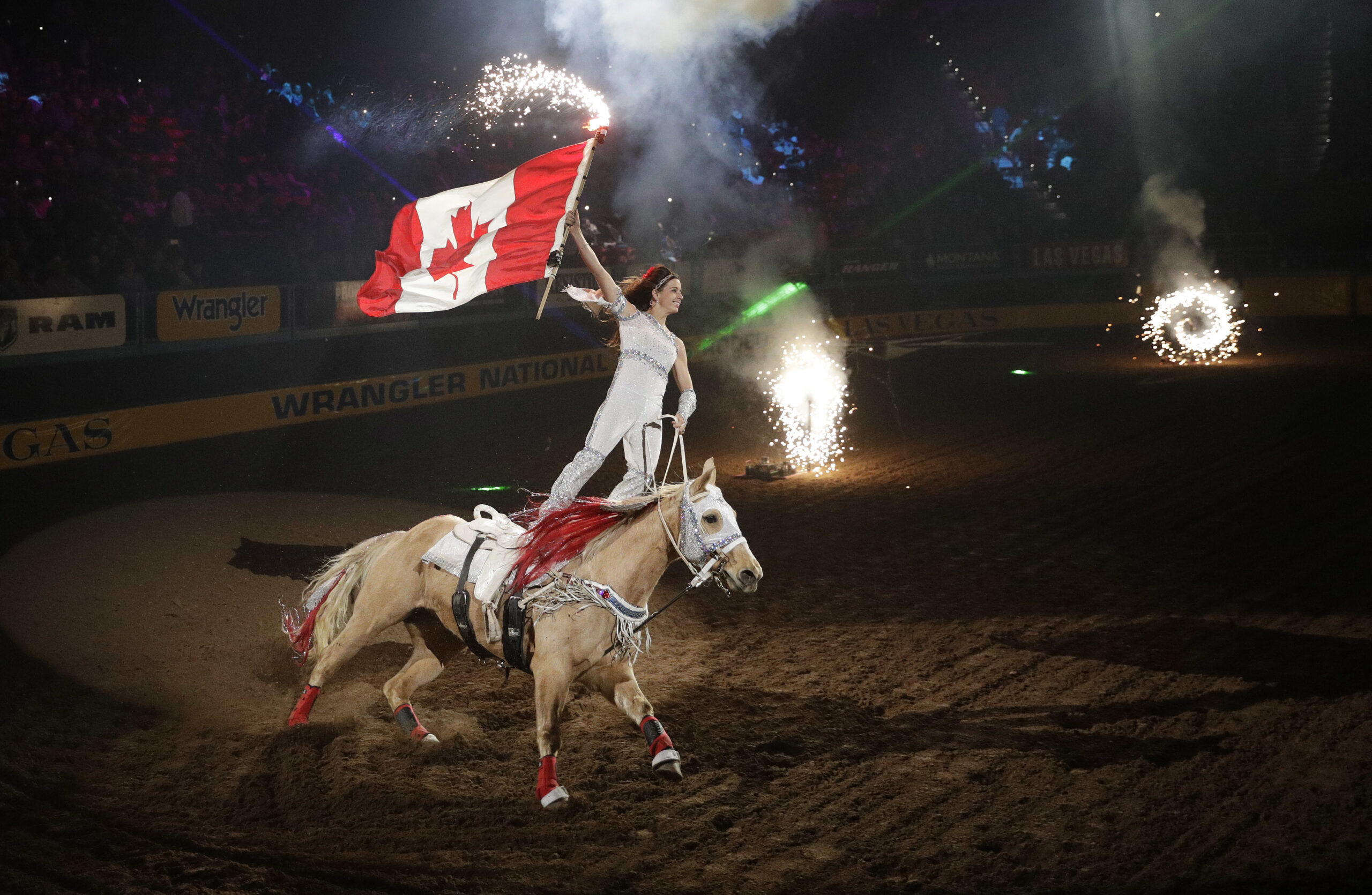 A rider carries the Canadian flag before the eighth go-round of the National Finals Rodeo at the Thomas & Mack Arena in Las Vegas.