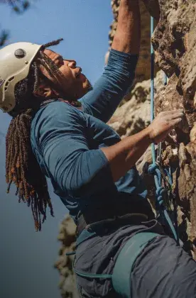 woman rockclimber halfway up cliff