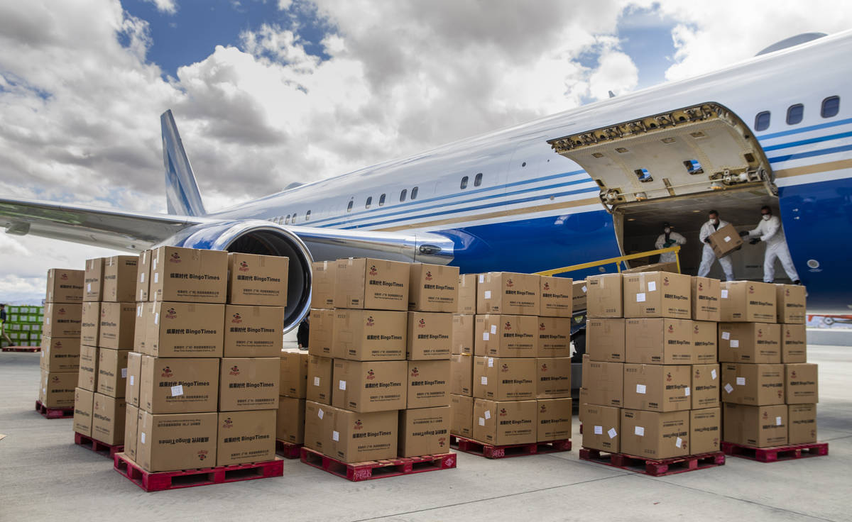 Transport workers stack some of the 1 million surgical masks arriving from Guangzhou, China, at ...