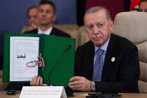 Turkey's President Recep Tayyip Erdogan holds a signed document during a summit to support ...