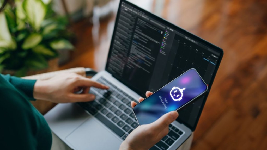 Asian woman using AI chatbot virtual assistance app on smartphone to assist her while working on laptop. Using AI technology while working at home. Online robot system. Concept of VR and AR technologies. People, AI, innovation and technology